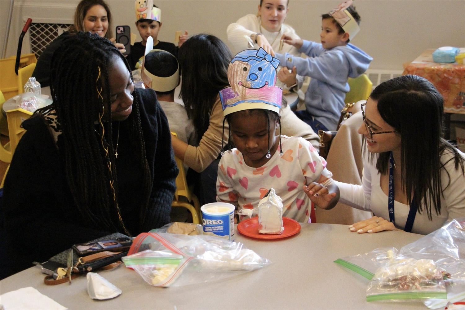  Heights Kindergarten teacher Sabrina Roy with a young student and her mother making gingerbread hou